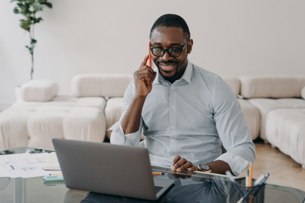 African american businessman talking on phone at laptop advises client, sells, conducts negotiations
